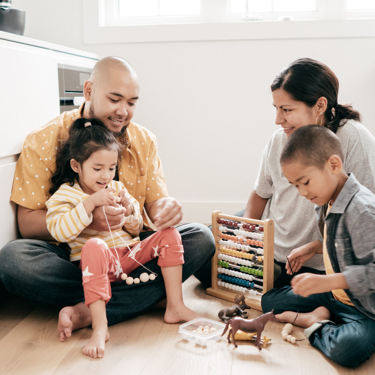 A family of 4 playing with toys on the floor